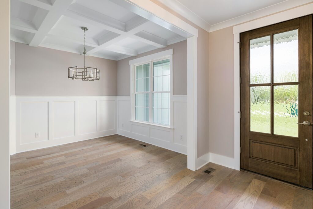 A modern interior featuring a wooden door, chandelier, and parquet flooring with large windows.